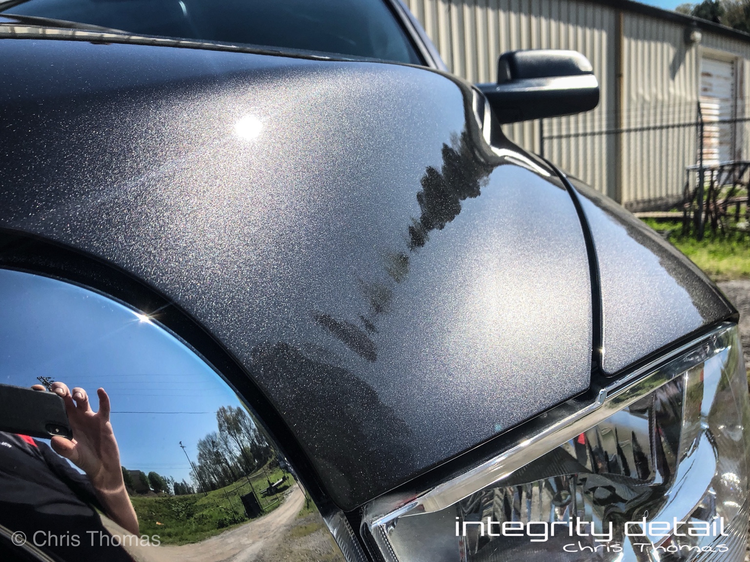 Close-up of glossy metallic gray paint on the ceramic-coated Ram hood, with Integrity Detail watermark