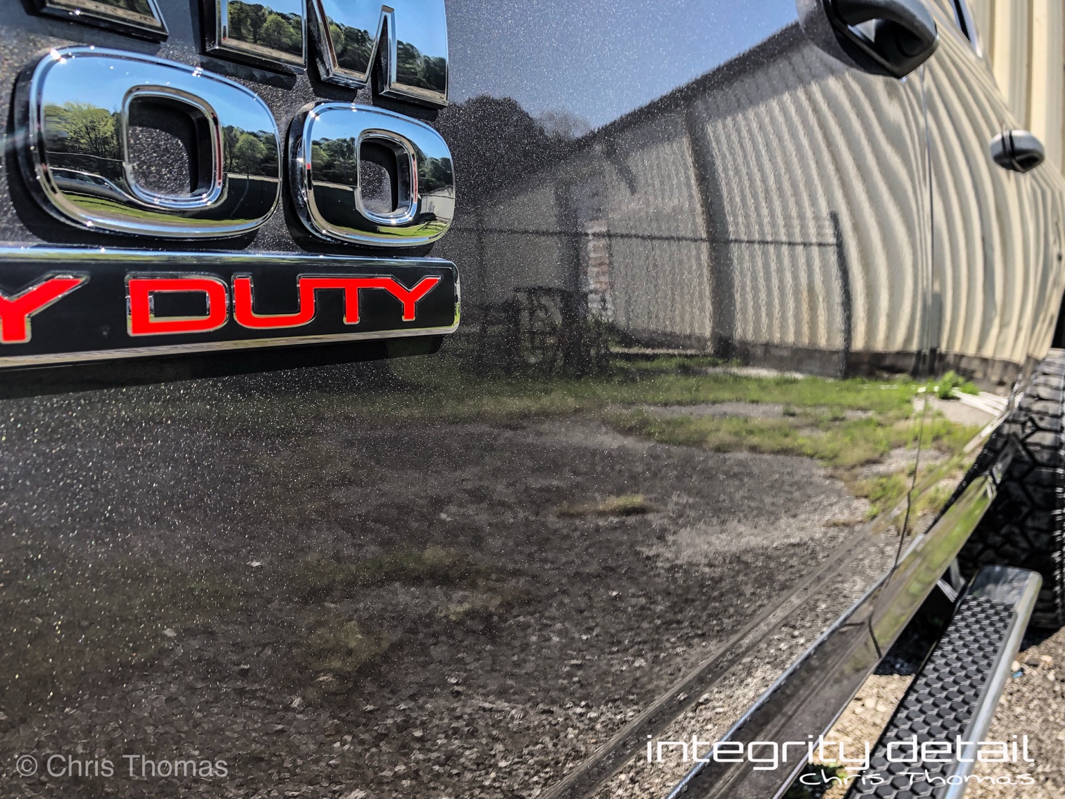Close-up of the ceramic-coated Ram side panel reflecting the shop and surroundings, with Integrity Detail watermark