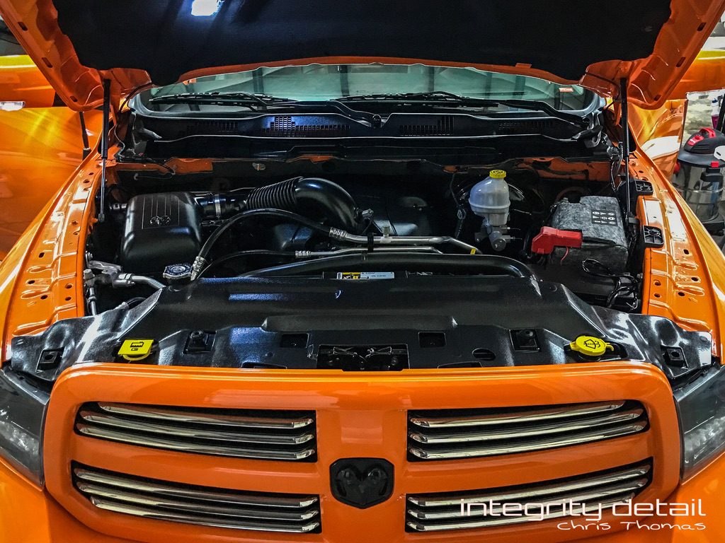 Clean engine bay of an orange Ram truck detailed at Integrity Detail