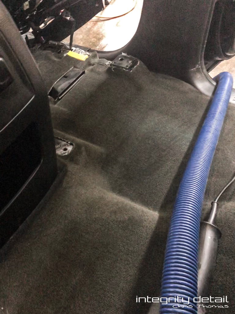 Clean vehicle carpet and seat mounting area after seats-out interior detailing