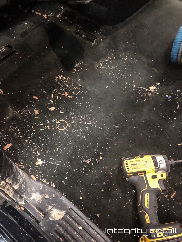 Debris and dirt on vehicle carpet exposed after removing the seat, before cleaning