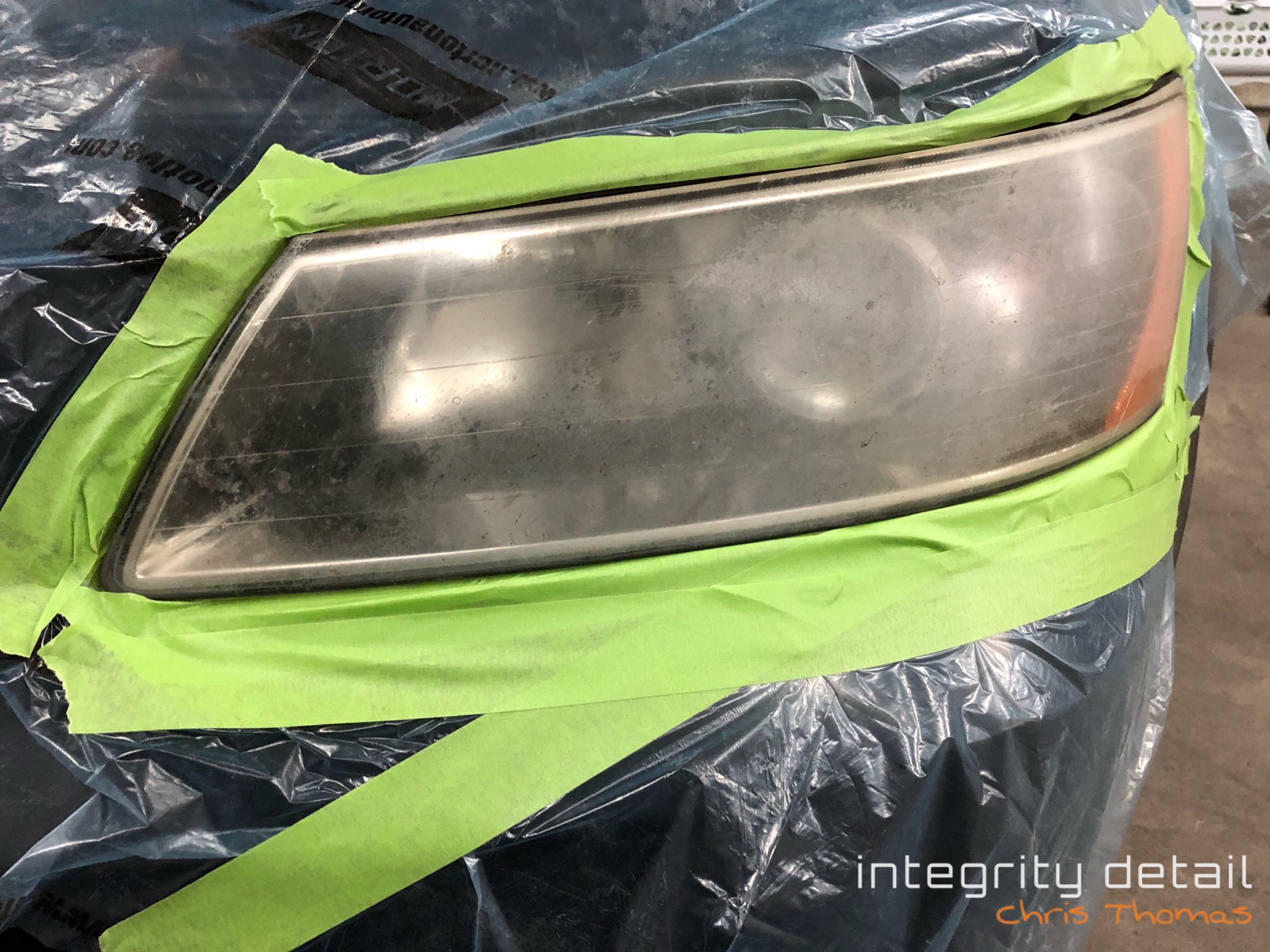 Before Integrity Detail headlight restoration: a cloudy exterior lens, with surrounding bodywork masked for protection